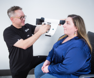 An optometrist using a portable fundus camera on a patient