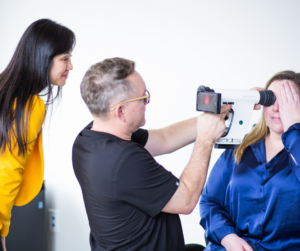 Optometrist using portable retinal camera on patient